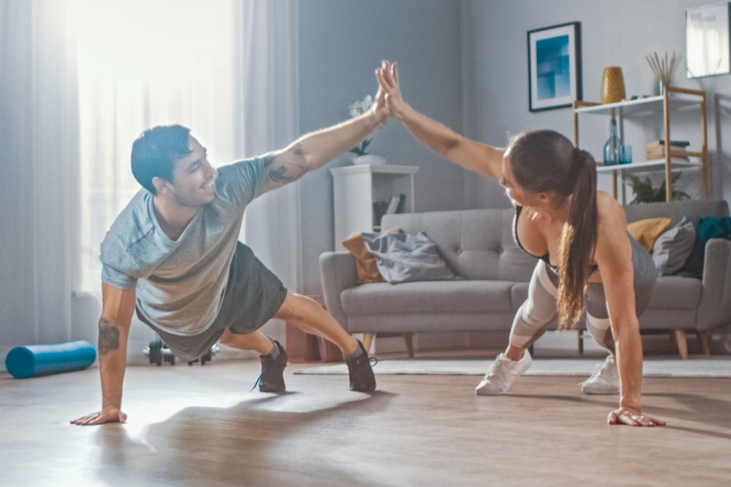 Athletic Fitness Couple in Workout Clothes Doing Push Up Exercises and Giving Each Other a High Five.