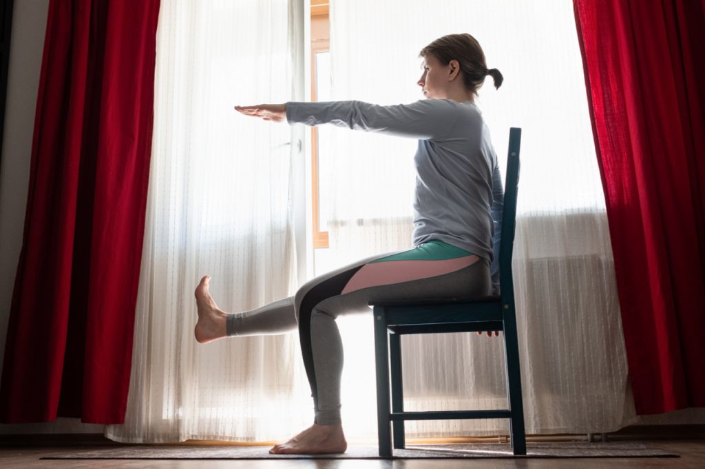 Woman doing exercises at home sitting on chair.