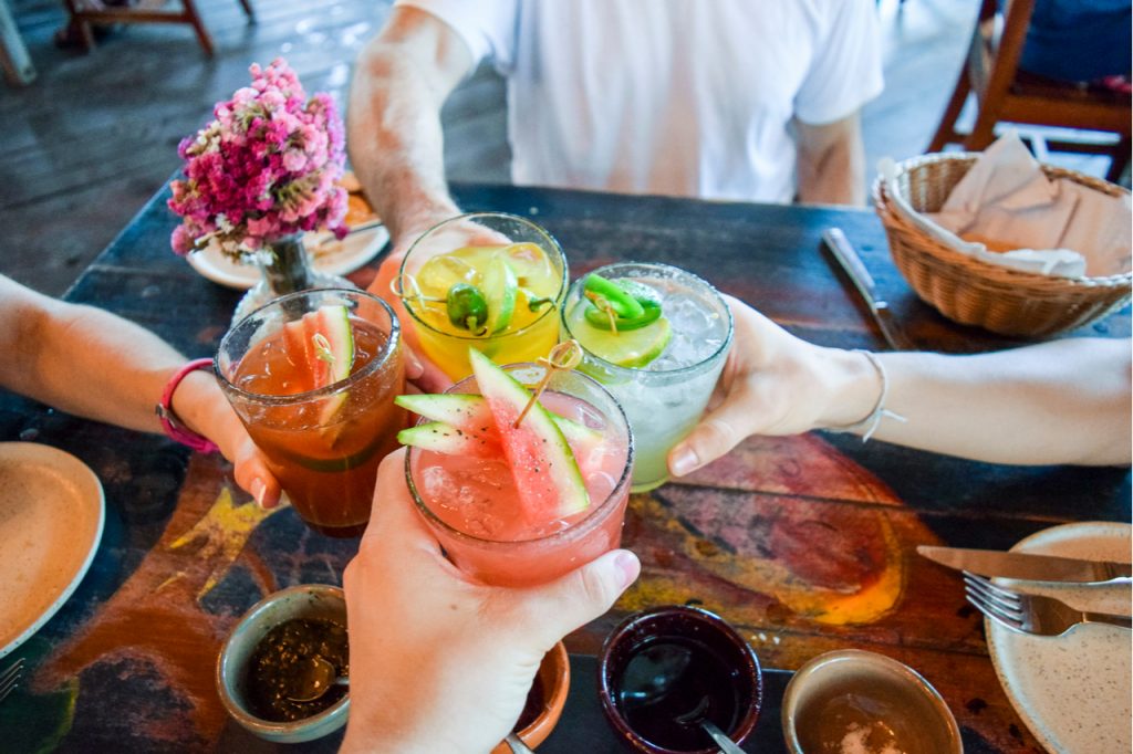 Friends clinking glasses with fruity alcoholic drinks at a party.