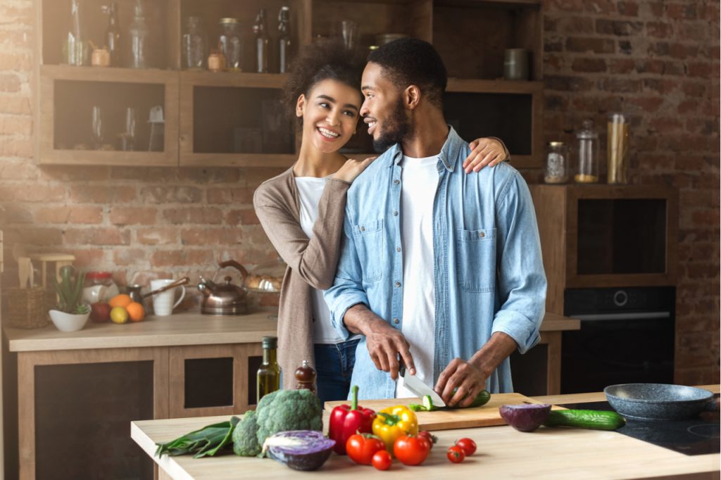 Loving couple preparing salad in loft kitchen at home.