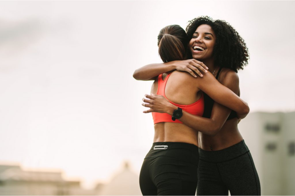 Cheerful female athletes embracing each other after workout.