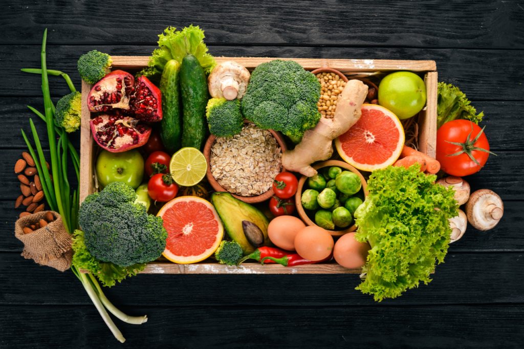 Fresh seasonal food vegetables, nuts and fruits in a wooden box.