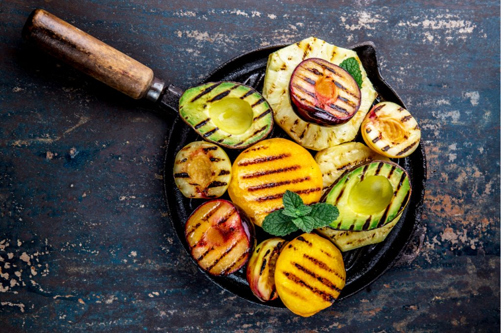 Grilled avocado, peaches, pineapple,
and plums on a black cast iron pan.