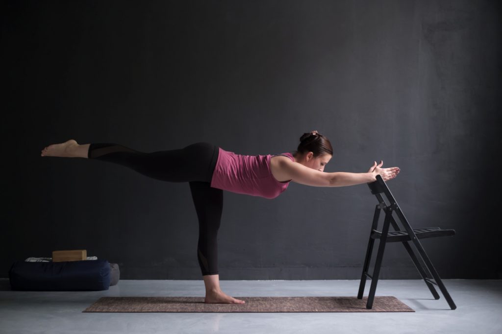 Woman doing hamstring kick chair exercise.