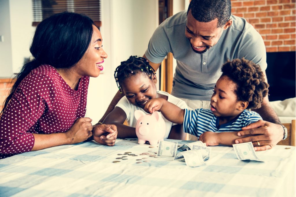 Family saving money to piggy bank learning what is financial wellness.