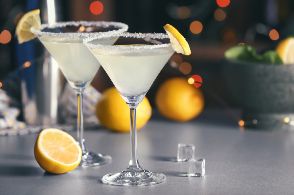 Glasses with tasty lemon drop martini cocktail on table.
