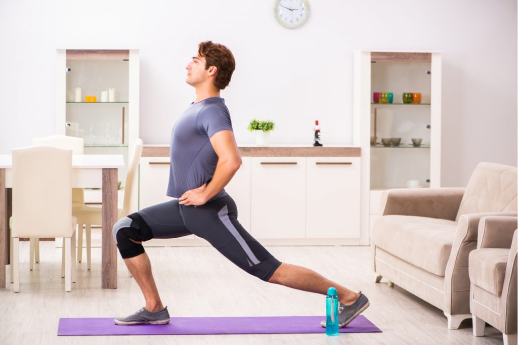 Man exercising with voodoo floss band for injury recovery.