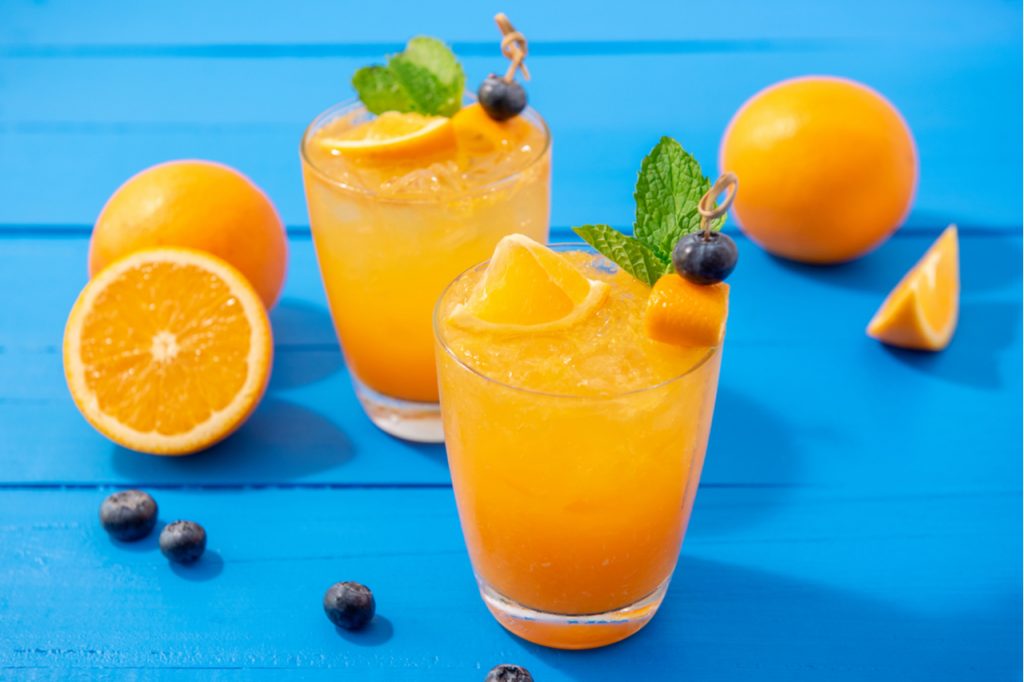Two orange cocktails on a blue table.