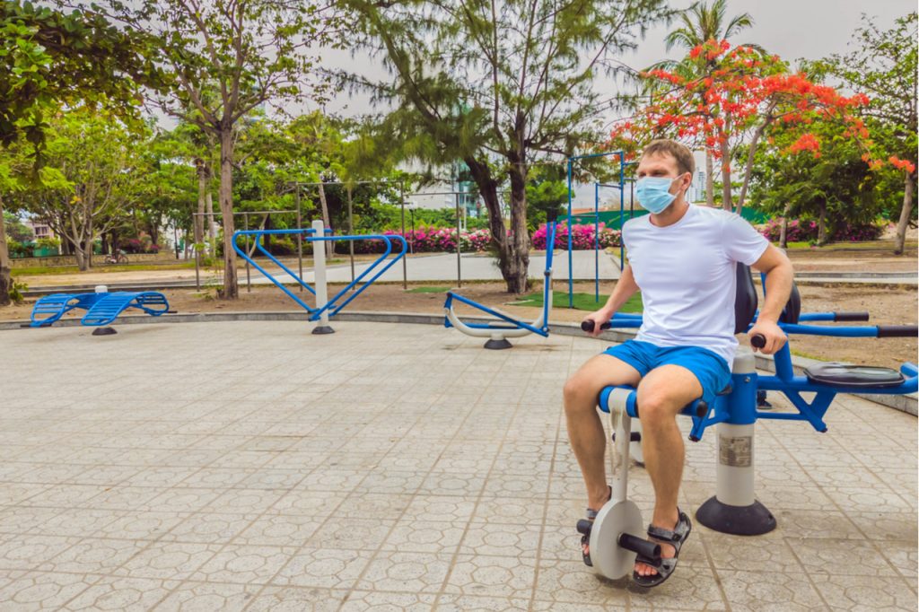 Man working out at the park using a leg machine.