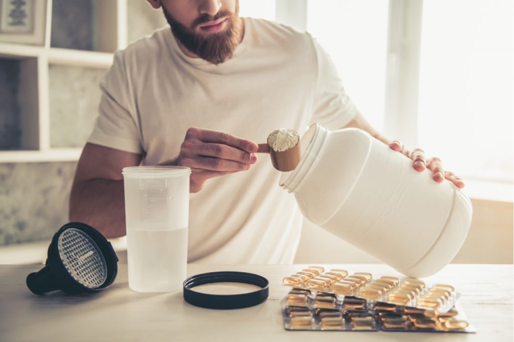 Cropped image of handsome young sportsman preparing sport nutrition in kitchen at home