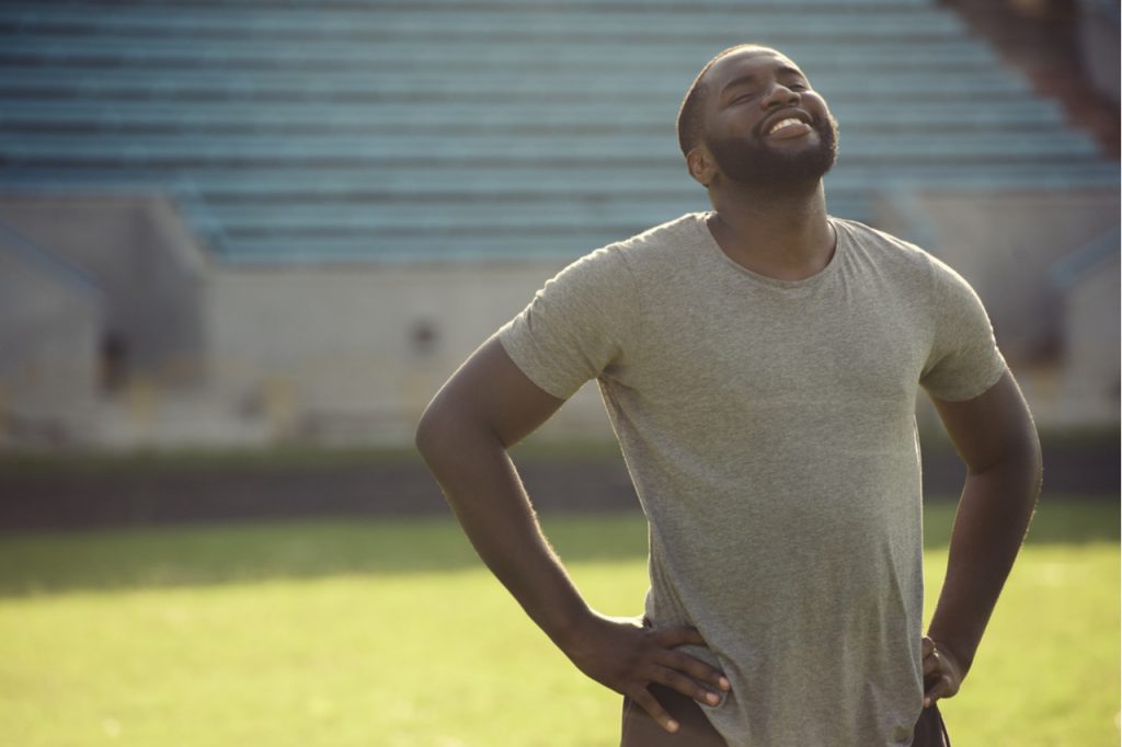 Man is feeling happy and relaxed, resting after workout in the field.