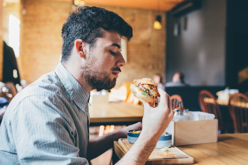 Man is eating in a restaurant and enjoying delicious food