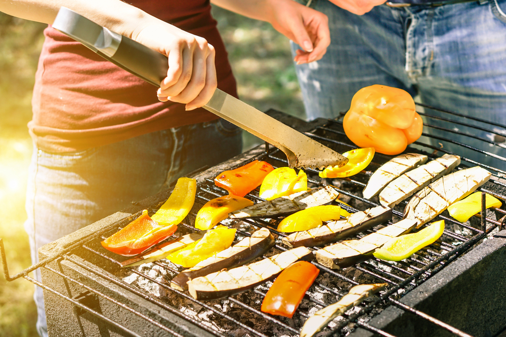 A woman grilling vegetables outdoors.