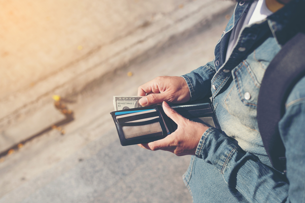 Hipster man hands holding wallet with credit cards and stack of money.