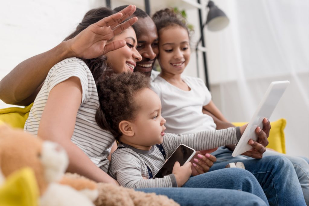 Happy young family making video call with tablet at home.