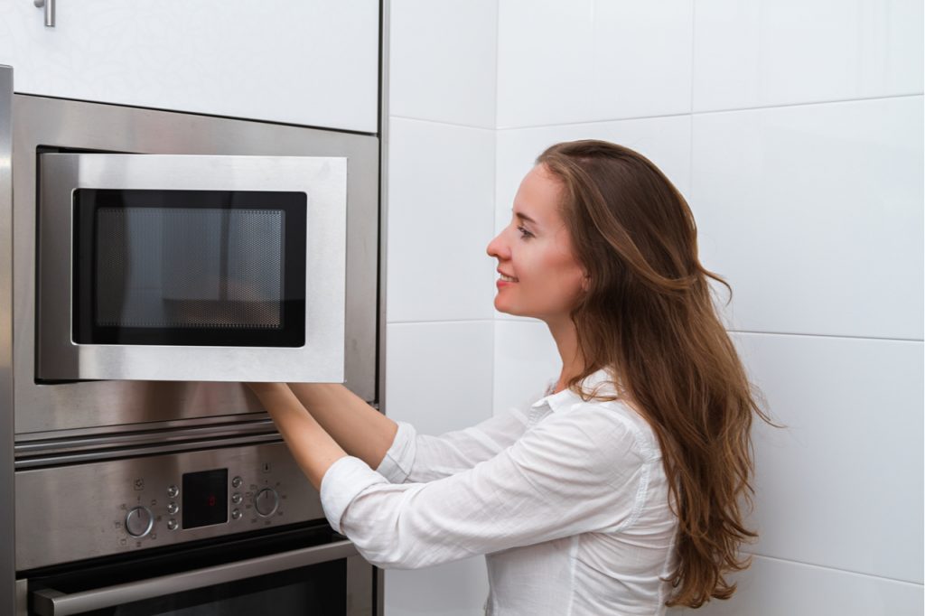 A woman microwaving frozen vegetable.