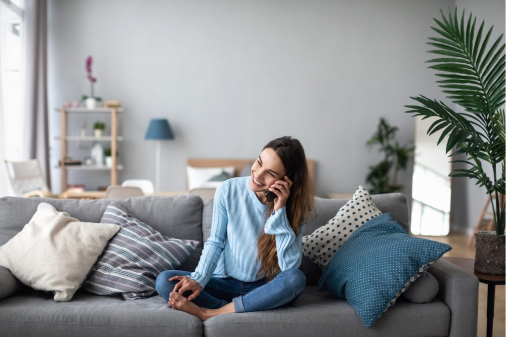Smiling woman talking on the phone at home on the sofa.