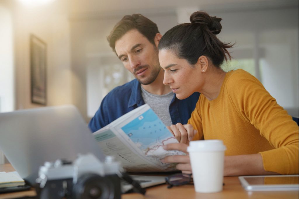 Couple planning their trip looking at map at home.