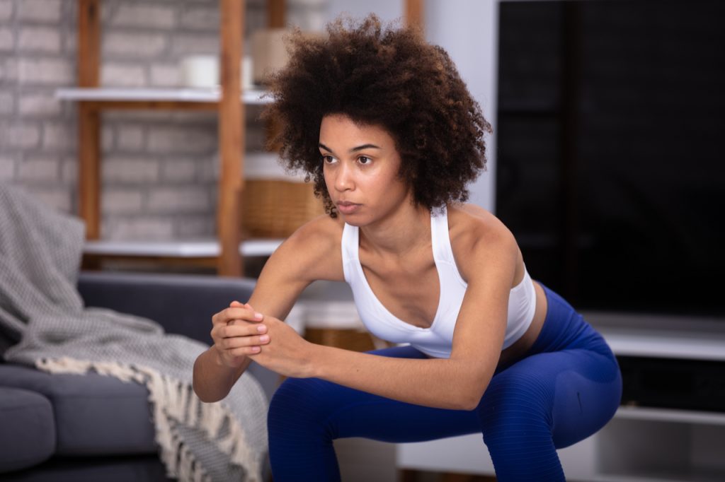A fit African-American woman doing squats.