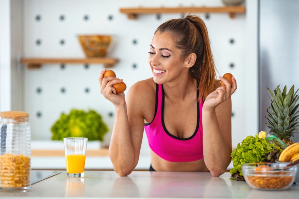 A sporty woman feeling happy to be prepping some eggs before workout.