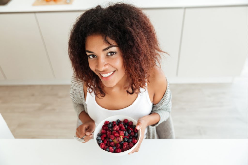 An African American woman holding a bowl of berries.