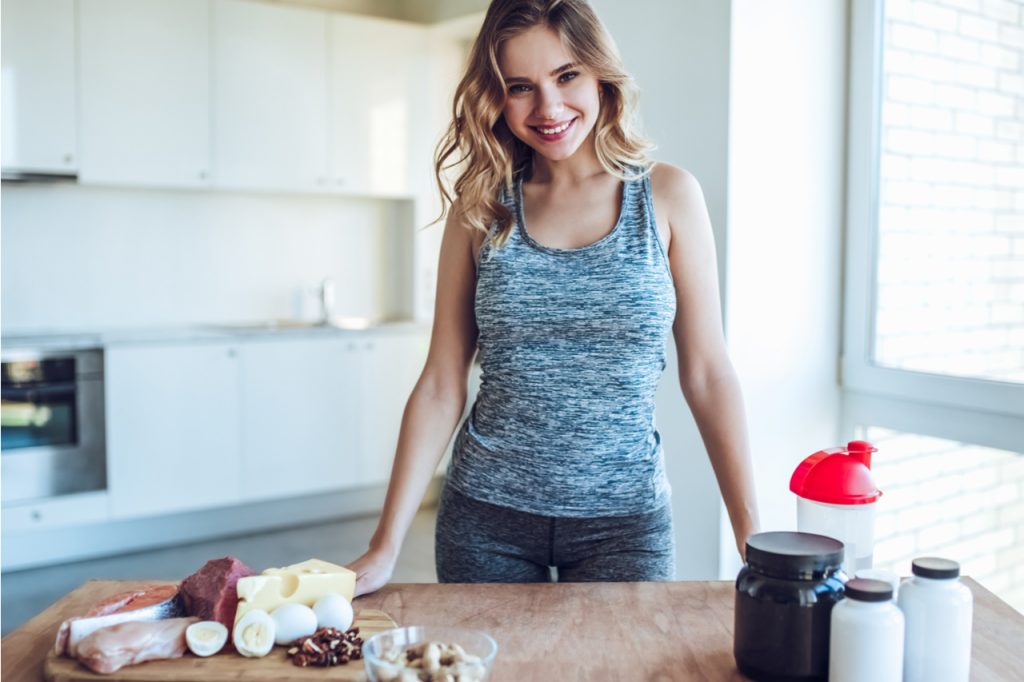 What is protein? Here's an image of a sporty-looking woman with protein rich foods and protein powder containers.