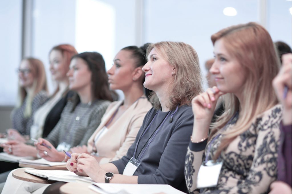 Several women focused on listening and learning in a conference or seminar.