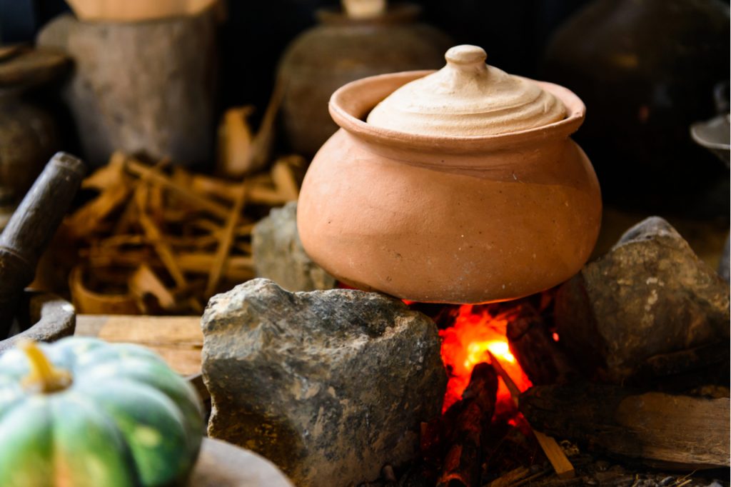 A traditional cooking pot on high flame to boil food.