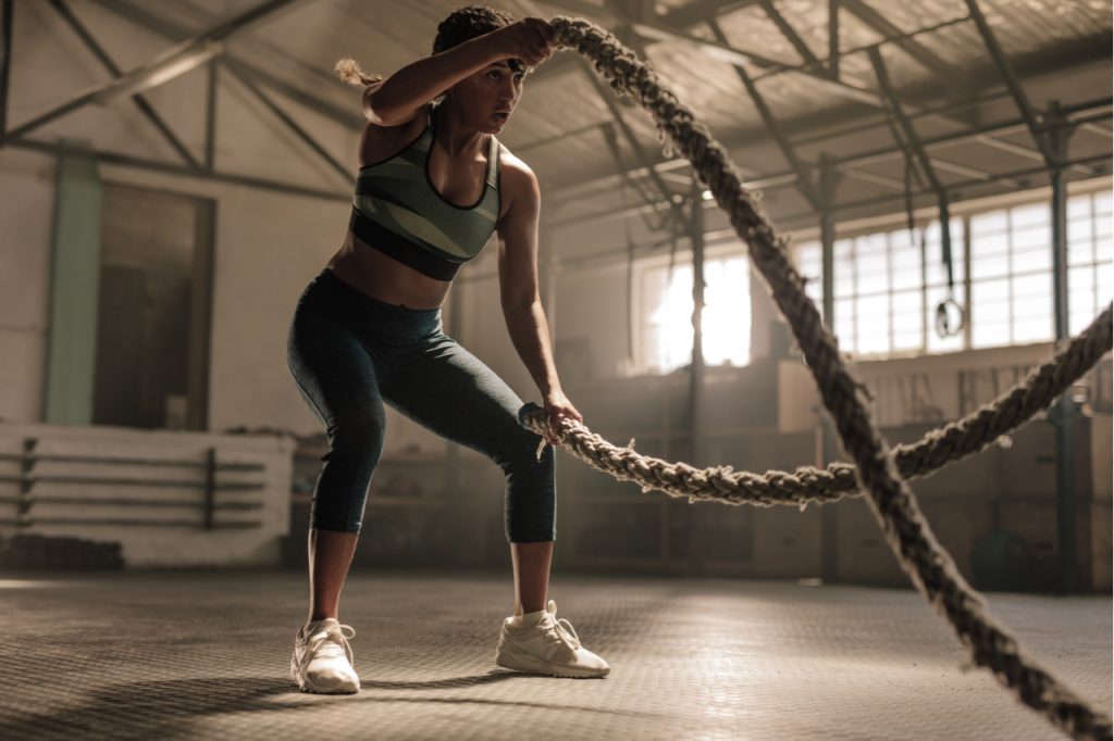 Fitness woman using Bonnlo Battle Ropes for exercise at gym.