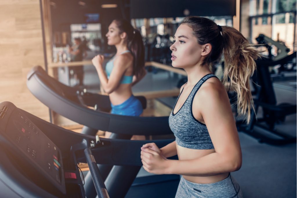 Side view of two attractive sports women on running track.