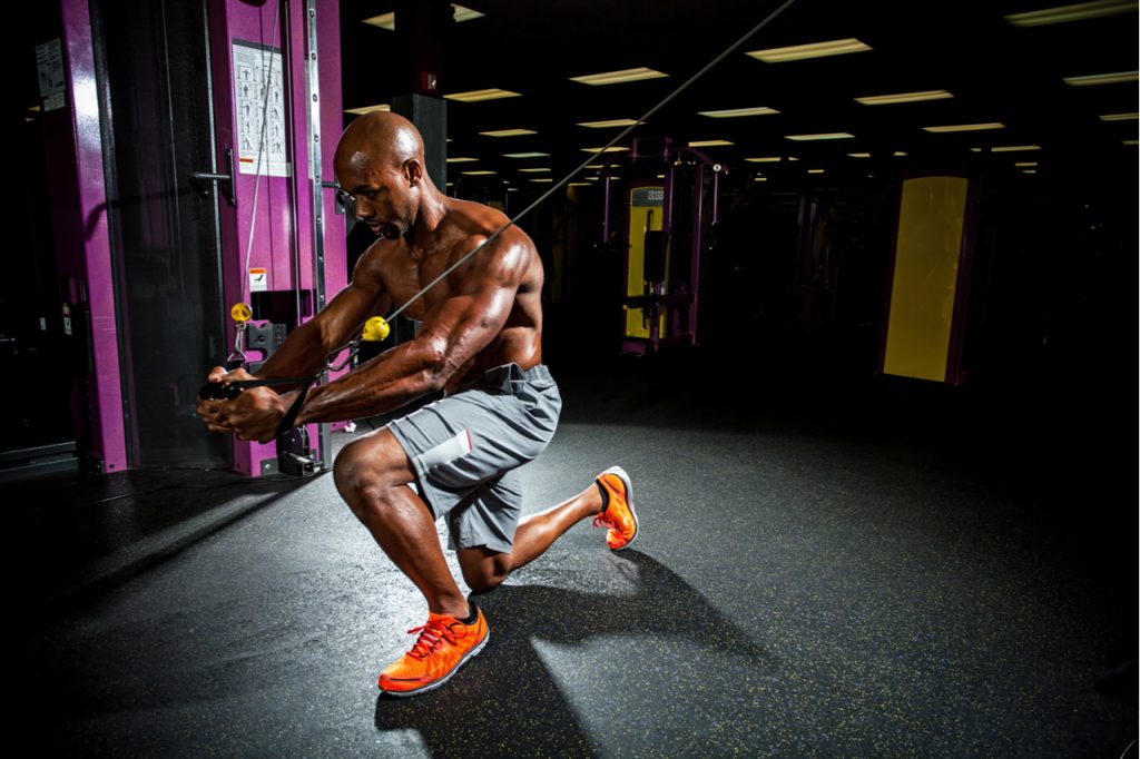 Muscular body builder working out at the gym doing chest fly exercises on the wire cable machine after taking TBN Labs Glyco Car Bomb.