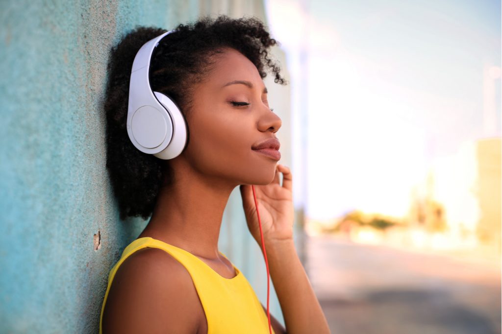 Pretty girl listening music with her headphones in the street.