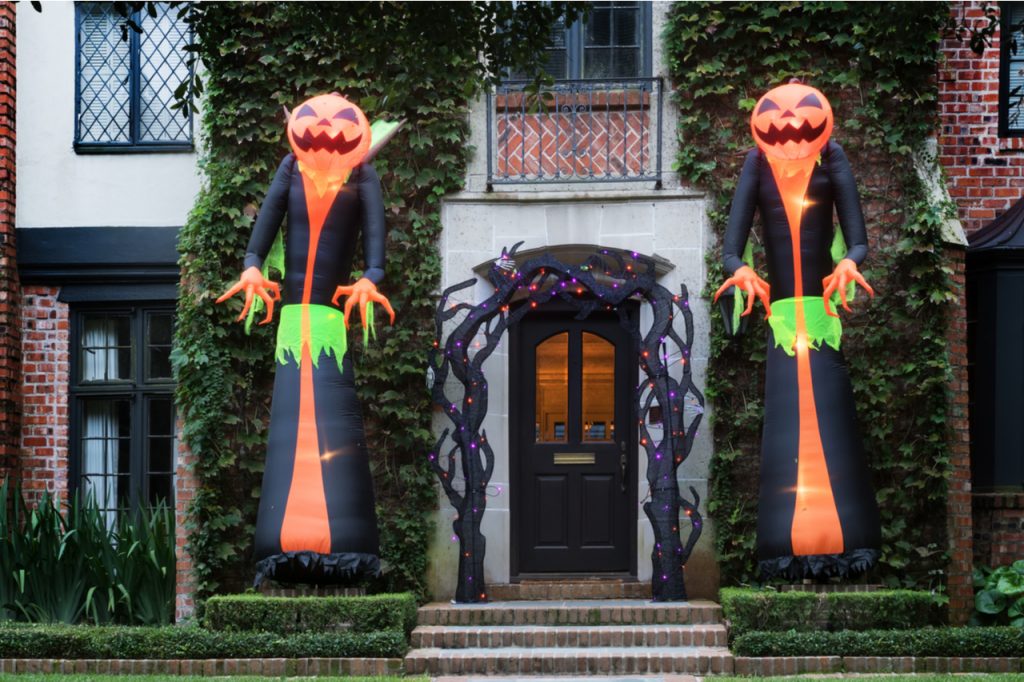 Two huge inflatable monsters with pumpkin heads stand at the entrance to the house.