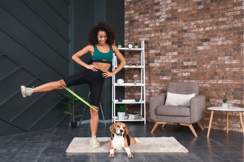 Sporty woman with cute dog training at home.