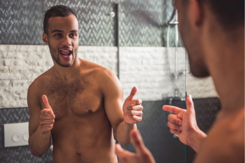 Man is winking at himself while looking into the mirror in bathroom.