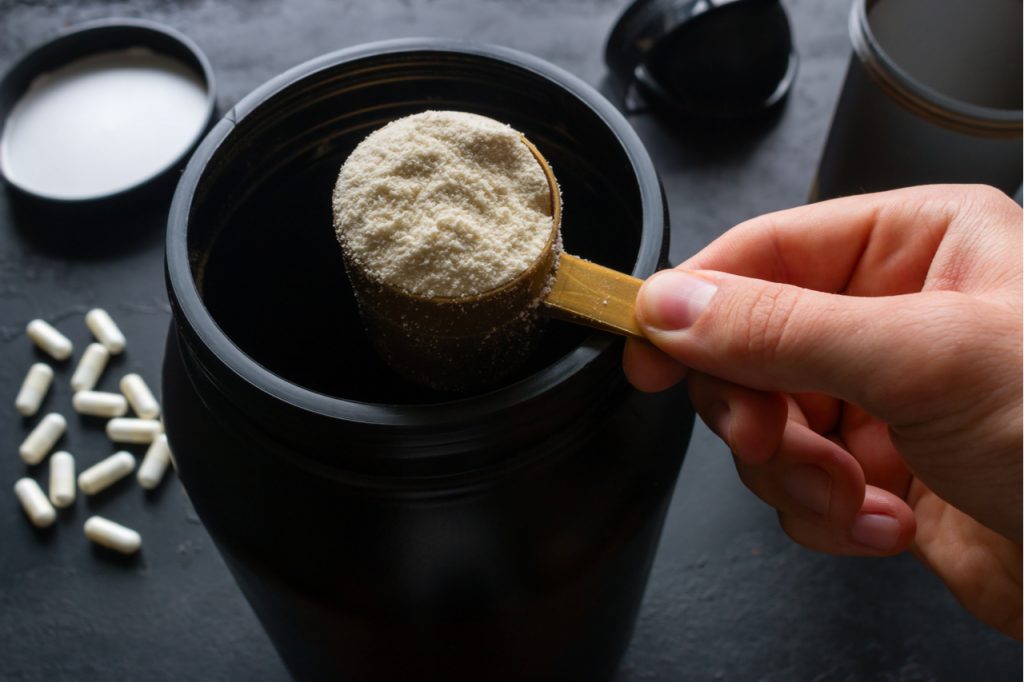 Man holding a measuring spoon of muscletech platinum creatine monohydrate powder.