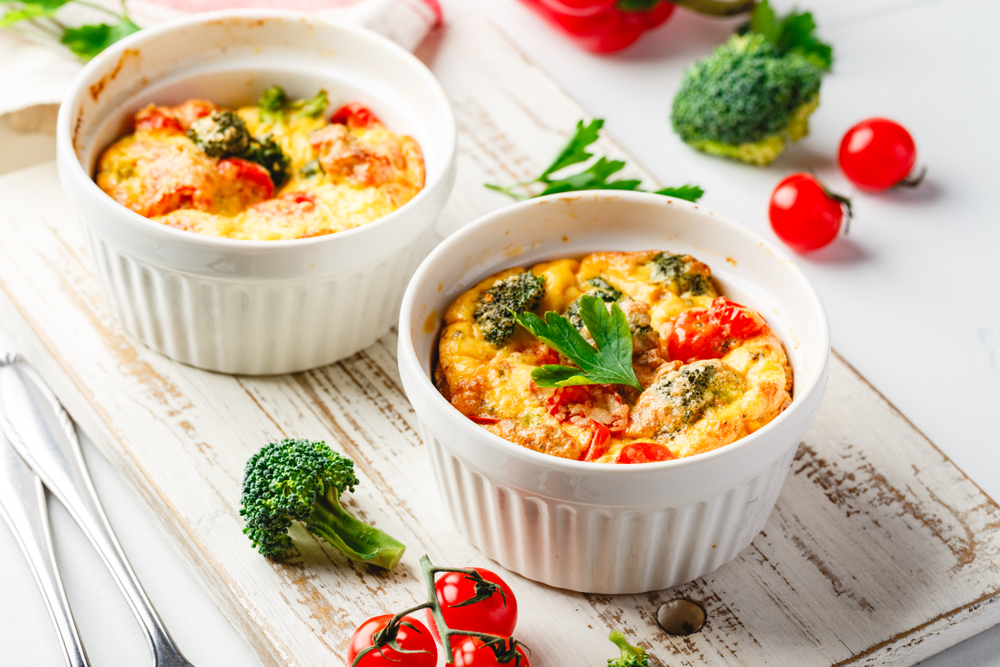 Frittata with broccoli in two ceramic forms. Frittata with broccoli, sweet bell peppers and tomatoes in two ceramic forms for baking. Italian omelet with vegetables