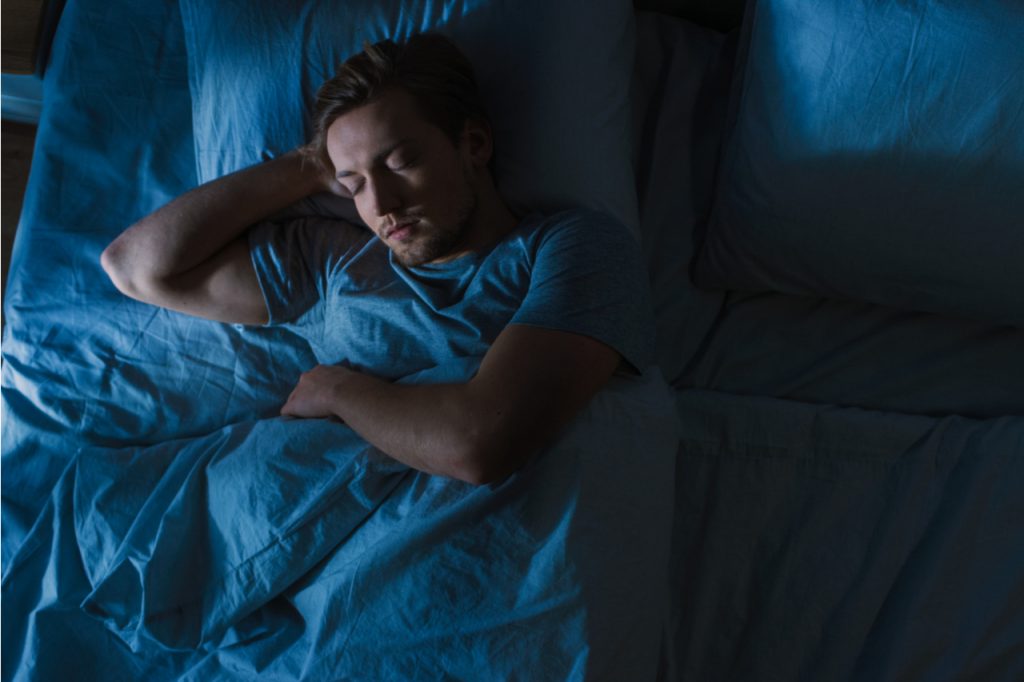 Man sleeping comfortably on his bed.