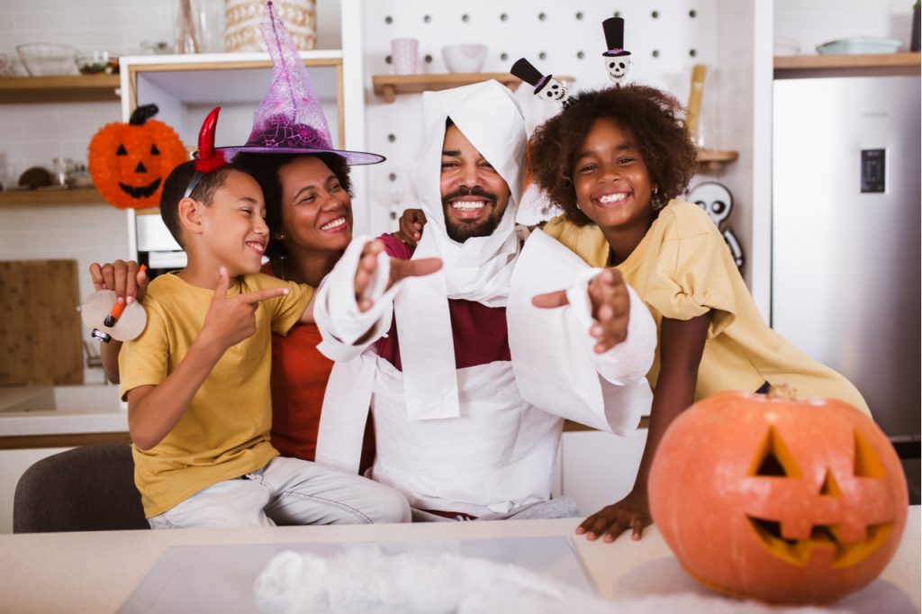 Happy family preparing for Halloween 2020, having fun.