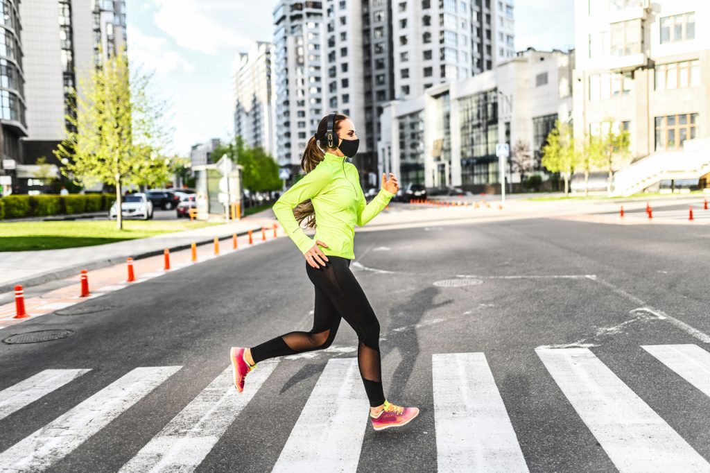 A fit woman doing her morning run with a face mask.