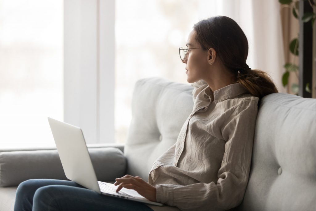 Woman in eyeglasses sitting with computer on couch lack of focus.