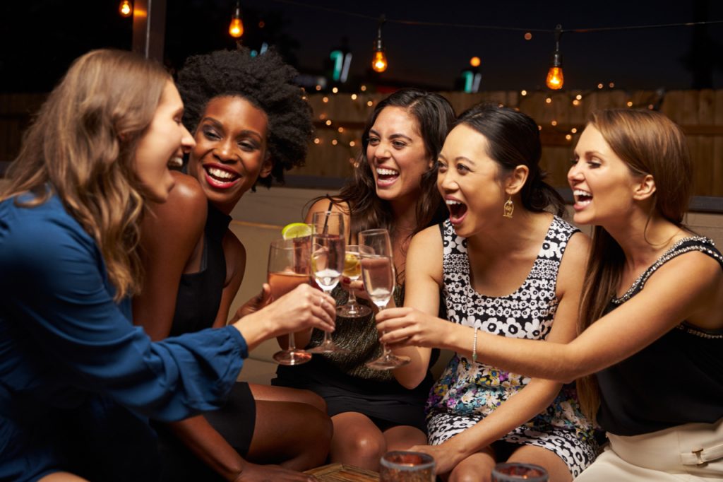 Group Of Female Friends Enjoying Night Out At Rooftop Bar