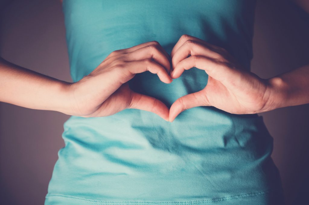 Woman hands making a heart shape on her stomach, healthy bowel degestion, probiotics and prebotics for gut health.