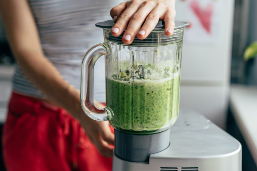 Close-up blender process. Cooking a green spring smoothie. Mixing in a blender bowl.