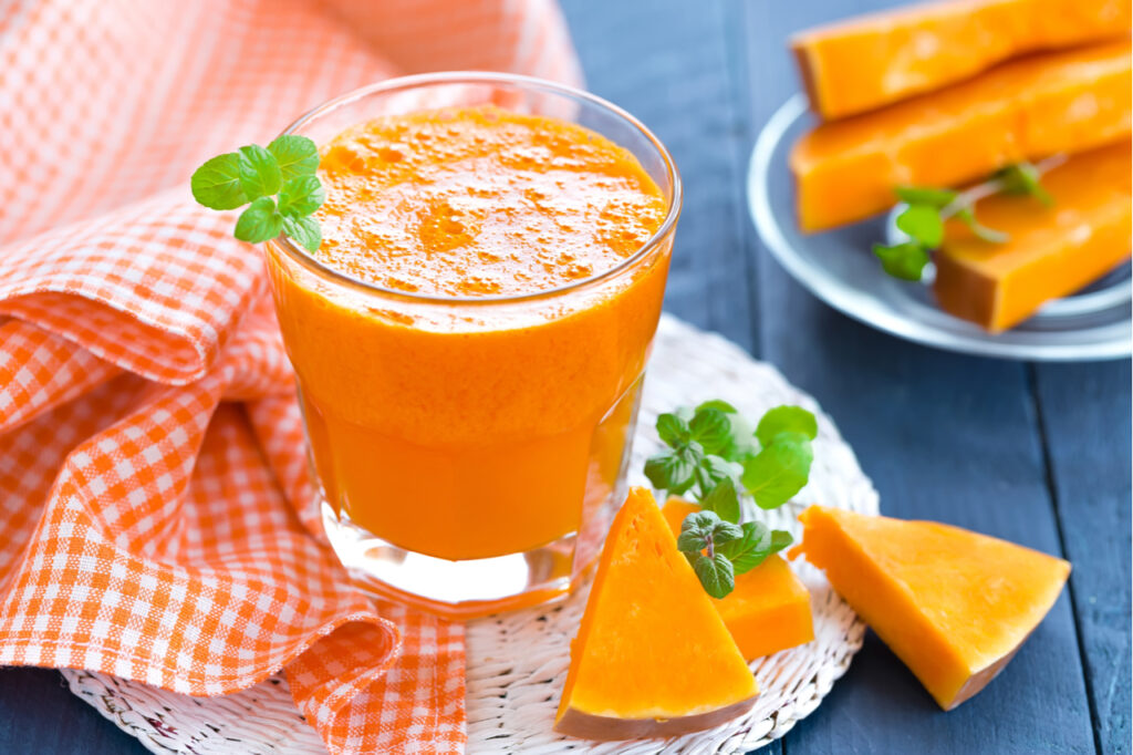 A glass of pumpkin juice on wooden table.