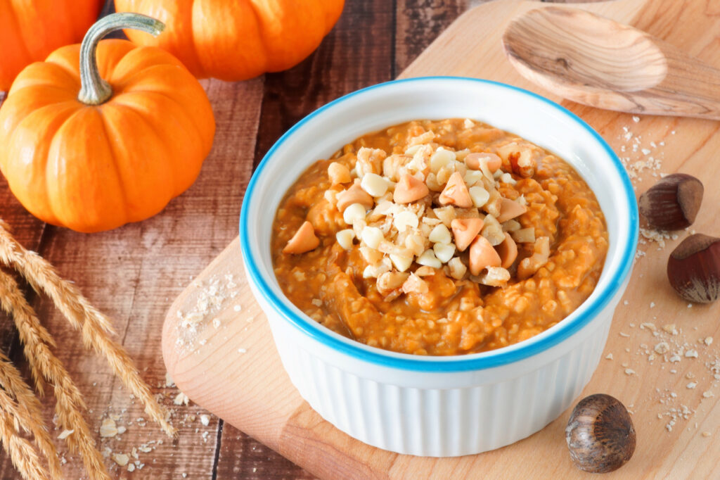 Bowl of autumn pumpkin oatmeal with walnuts, chocolate and peanut butter chips, table scene