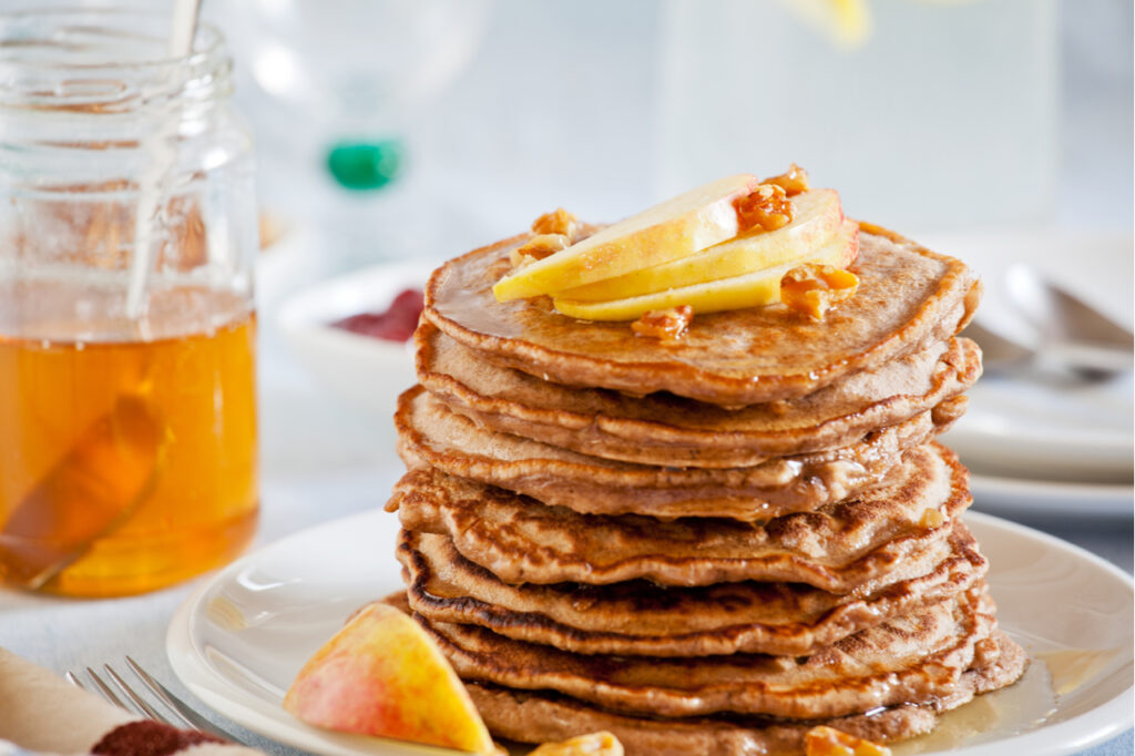 Stack of homemade whole wheat pancakes with fruits and nuts is a good holiday breakfast idea.