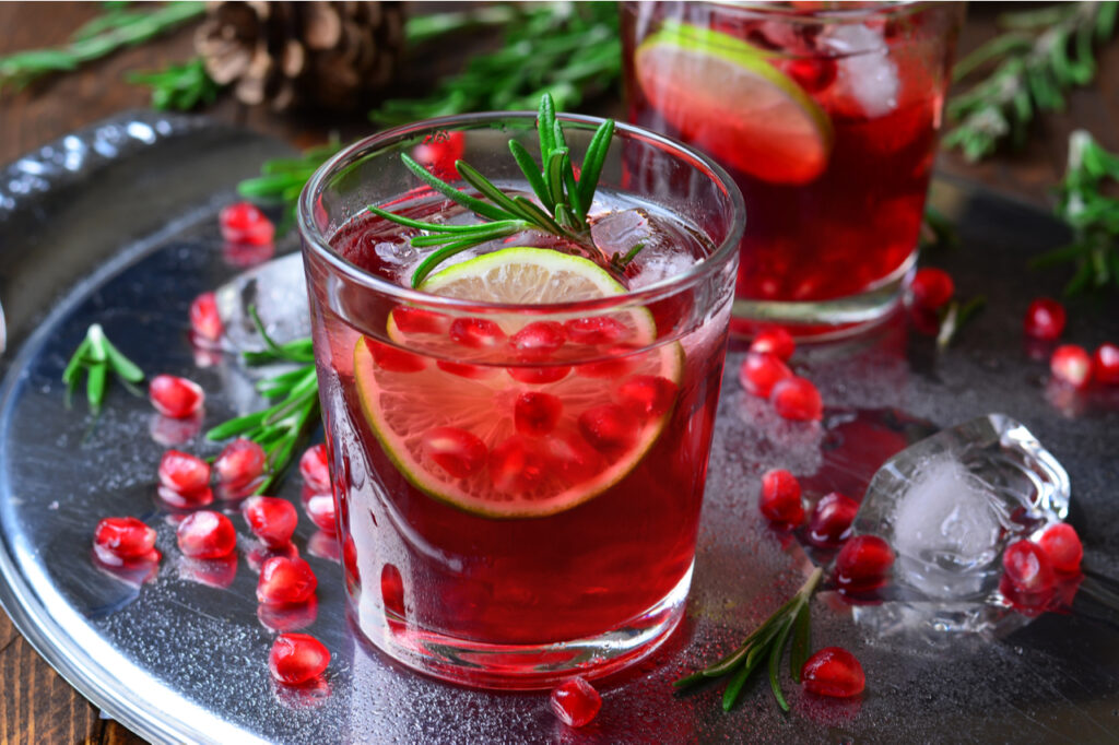 Two glasses of pomegranate mocktail on a silver serving tray.