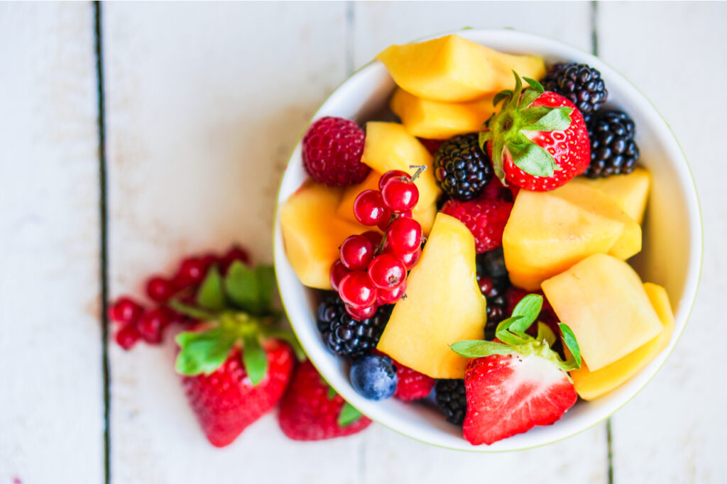 Fruit salad made with different berries and grapes in a white bowl.