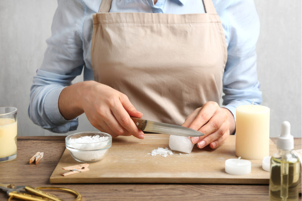 A woman slicing a candle in a chopping board to make decorative candles.